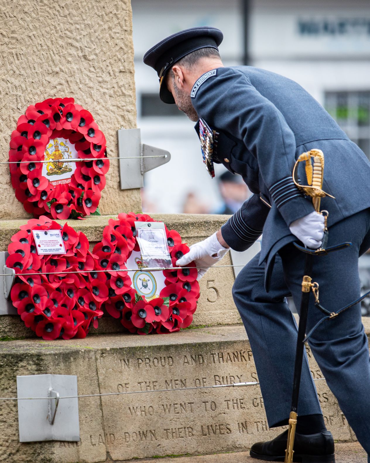 Image shows RAF aviator laying wreath on memorial.